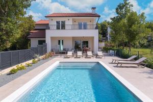 a villa with a swimming pool in front of a house at Villa Hidden with heated pool in Dobrinj