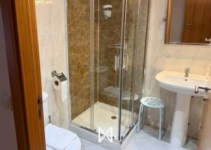 a shower with a glass door next to a sink at MyStay - Casa Miná in Montalegre