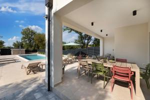 a patio with a table and chairs and a pool at Villa Hidden with heated pool in Dobrinj