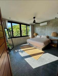 a bedroom with a large bed in a room with windows at Casa Malayka in Uluwatu
