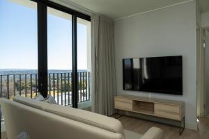a living room with a white couch and a flat screen tv at One Rosebank Executive Apartment Hotel in Johannesburg
