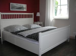a white bed in a bedroom with a red wall at Fewo Düsterbarg in Wittenbeck