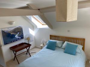 a bedroom with a bed with blue pillows and a table at Little Llanvolda in Saint Maughans