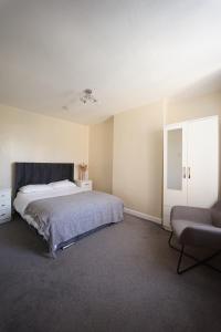 a bedroom with a large bed and a chair at Maidstone Gem Walk to Shops in Maidstone