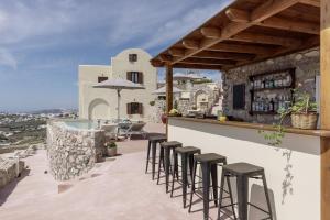 a bar on the roof of a house with stools at Zatrikion Santorini Villas in Pirgos