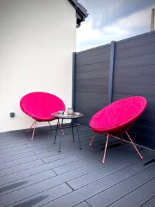 two pink chairs and a table on a patio at L'Escale de la Râperie logement2 in Tincourt-Boucly