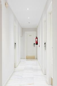 an empty hallway with white walls and a white floor at Hotel Toboso Chaparil in Nerja