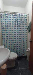 a bathroom with a toilet and a shower curtain at Hospedaje Dase in Oxapampa