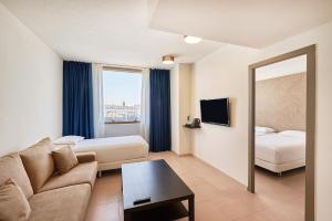 a hotel room with a couch and a bed and a mirror at Hesperia Sant Joan in Sant Joan Despí