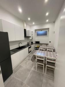 Una cocina con gabinetes blancos y una mesa con sillas. en OIKOS b&b, en Galatina