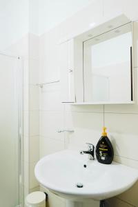 a white bathroom with a sink and a mirror at Sunny View Apartment in Sarandë