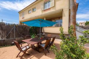 a table with a blue umbrella in front of a house at Casa Luz Cala Rajada in Cala Ratjada