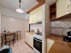 a kitchen with white cabinets and a table and a stove at CalvinForumGreatChurchMainSquare in Debrecen
