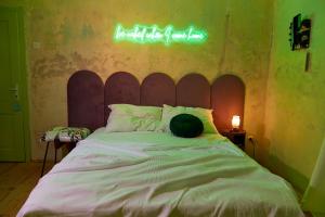 a bedroom with a bed with a neon sign on the wall at Alma ART B&B in Dobrovo