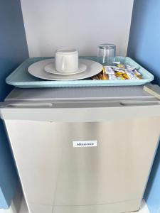 a plate and a cup on top of a refrigerator at Drifters Haven Gqeberha in Gqeberha