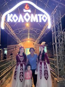 a woman and three girls standing in front of a sign at Коломто in Bokonbayevo