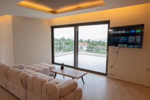 a living room with a couch and a table and a large window at White Sand Loutraki Villa - Sea View in Loutraki