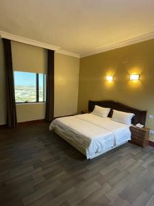 a hotel room with a bed and a large window at فندق زهوان للضيافة السياحي in Al Buwaţah