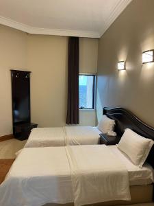 a hotel room with two beds and a window at فندق زهوان للضيافة السياحي in Al Buwaţah