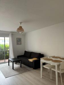 a living room with a black couch and a table at CAPUCINES - T2 ANGLET avec stationnement in Anglet