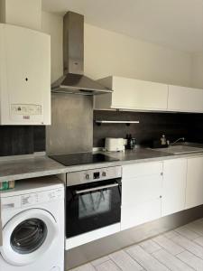 a kitchen with a stove and a washing machine at CAPUCINES - T2 ANGLET avec stationnement in Anglet +4 photos