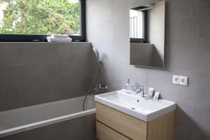 a bathroom with a sink and a mirror and a tub at Gardinn Apartments - Hotel Service and Free Parking in Bratislava