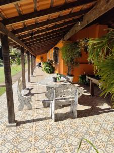eine Terrasse mit Tisch und Bänken und ein Gebäude in der Unterkunft Pousada Campestre Cunha-SP in Cunha