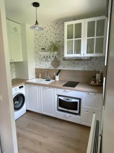 Una cocina con gabinetes blancos y lavadora y secadora. en Cozy appart between Paris & Disney, en Torcy