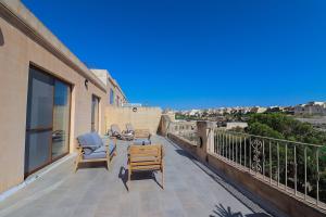 a balcony with two chairs and a table on a building at Penthouse with Xlendi Views & Two large Terraces in Munxar