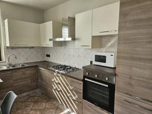 a kitchen with white cabinets and a stove and a microwave at A casa di Thelma in Barolo
