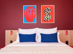 una camera da letto con un letto con tre dipinti sul muro di Numa Berlin Friedrichshain a Berlino