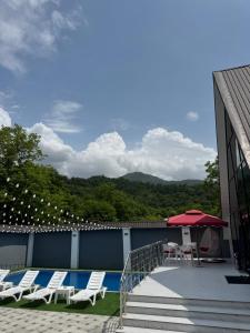 a deck with chairs and a table and an umbrella at AFrame Gabala Azerbaijan FF in Gabala