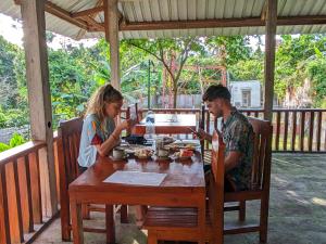 a man and a woman sitting at a wooden table at Senaru Guesthouse in Senaru