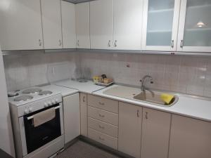 a kitchen with white cabinets and a sink and a stove at Απολαύστε τη διαμονή σας στις Σέρρες in Serres +10 photos