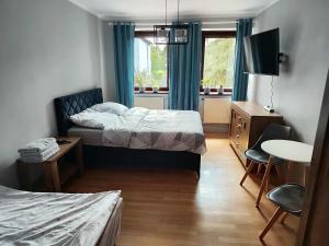 a bedroom with two beds and a table and a tv at Willa IDYLLA in Kołobrzeg