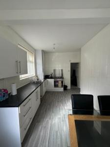a large kitchen with white cabinets and a wooden floor at Single bedroom 1 in Anfield in Liverpool +3 photos