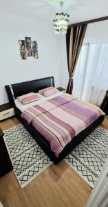 a bed with a striped comforter in a bedroom at Apartament Niki in Mangalia