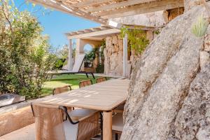 a wooden table on a patio with a stone wall at La Tiara di Cervo in Liscia di Vacca +26 photos
