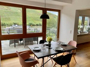 a dining room with a table and chairs and a large window at Ferienwohnungen Rees in Briedel