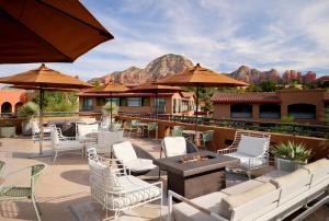 un patio con sedie bianche, tavoli e ombrelloni di The Wilde Resort and Spa a Sedona