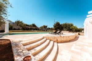 a swimming pool with benches and a stone wall at HelloAPULIA - Luxury Villa with saltwater pool in Antonelli +53 photos