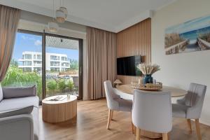 a living room with a table and chairs and a couch at Sol Marina - Pool, SPA, Wellness, Riverview & Parking by Downtown Apartments in Wiślinka