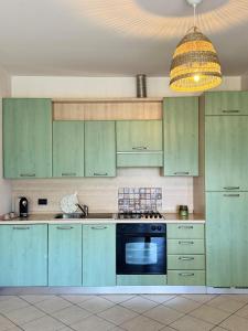 a kitchen with green cabinets and a blue oven at Casa Lagobello, Piscina e Relax sul Lago Maggiore in Germignaga +26 photos