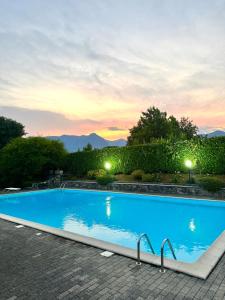 a large blue swimming pool with a sunset in the background at Casa Lagobello, Piscina e Relax sul Lago Maggiore in Germignaga