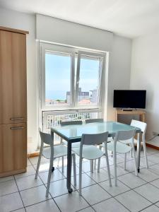 a dining room with a table and chairs and a television at Condominio Cam 78 in Lignano Sabbiadoro +8 photos