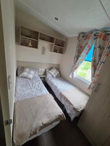 two beds in a small room with a window at Lovely Caravan number 96 at Three Lochs Holiday Park in Kirkcowan +23 photos