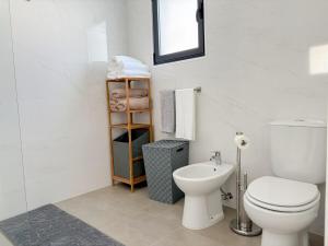 a white bathroom with a toilet and a sink at Casa Norbina in Ribeira Quente +9 photos