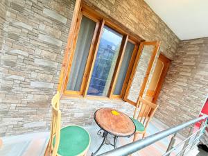 a table and chairs on a balcony with a window at WonderOn Stay & Cafe in Manāli