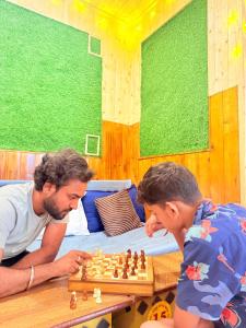 a man and a boy playing a game of chess at WonderOn Stay & Cafe in Manāli