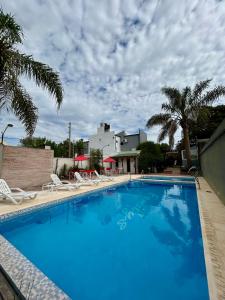 a large blue swimming pool with chairs and palm trees at Bungalows Familys in Concepción del Uruguay